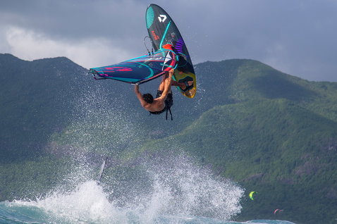 Duotone Skate SLS windsurf board during freestyle windsurfing on a tropical ocean with mountainous coastline