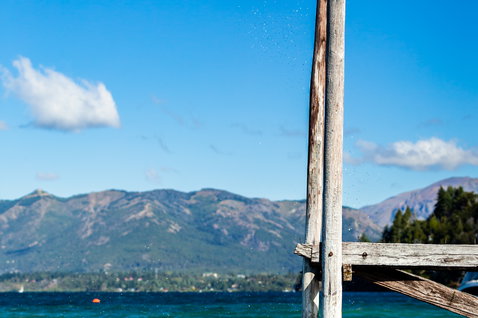 Duotone Gambler wake-style kiteboard during wakestyle on a lake with mountain backdrop and wooden dock