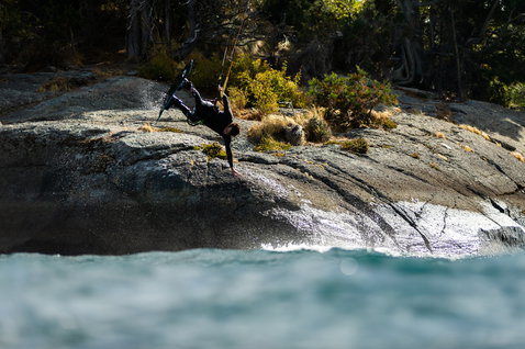 Duotone Gambler wake-style kiteboard during wakestyle kiteboarding at a rocky coastline with teal water