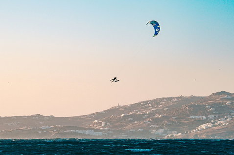 Duotone Rebel SLS 2024 LEI kite lors du kitesurf sur l'océan avec une ville côtière en arrière-plan