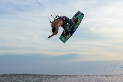 Duotone Jaime twin-tip kiteboard during kitesurfing freestyle aerial trick at ocean flat water shoreline