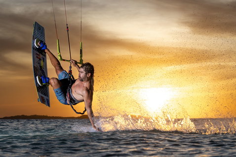 Duotone Select SLS twin-tip kiteboard during kitesurfing at an ocean beach at sunset