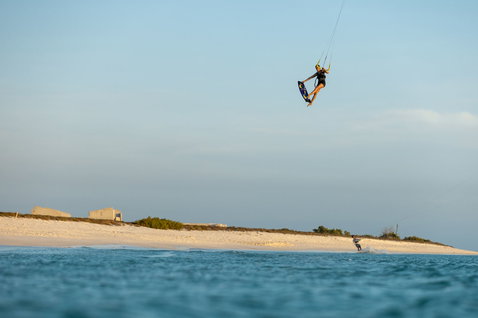 Duotone Soleil Concept Blue twin-tip kiteboard during kitesurfing at an ocean beach with white sand shoreline