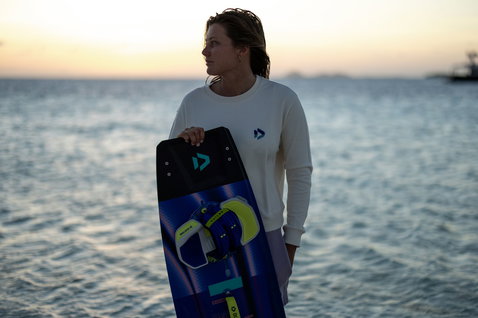 Duotone Entity Ergo 2024 Concept Blue twin-tip kiteboard at the water's edge on an ocean beach