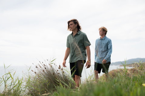 Duotone Apparel Shirt Wave Kurzarm-Hemd beim Tragen an der Küste mit Meerblick in staubigem olivgrün