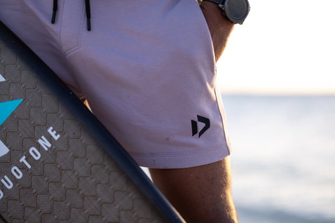 Duotone Shorts Sweat Onshore Sweat-Shorts Unisex in hellem Malve mit hellviolett-grau an einem Model am Strand
