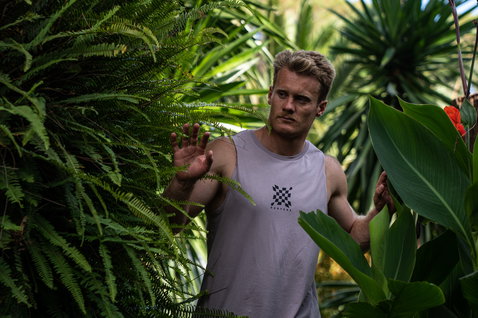Duotone Apparel Tank men tank top in mauve grey during a standing pose in a tropical garden