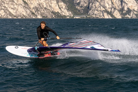Planche de windsurf Duotone Falcon Fin D/LAB lors de windsurf sur un lac alpin avec falaises rocheuses