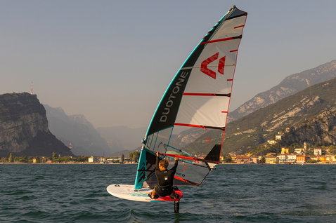 Duotone Warp Foil foil sail while foiling on an alpine lake with mountain backdrop and village
