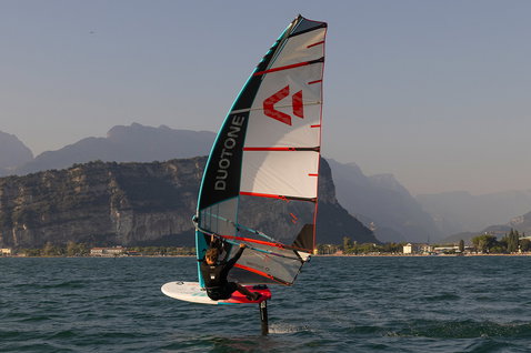 Duotone Warp Foil foil sail during foiling on an alpine lake with mountain backdrop
