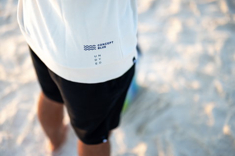 Moletom Duotone Concept Blue em off-white em pose na orla arenosa do oceano