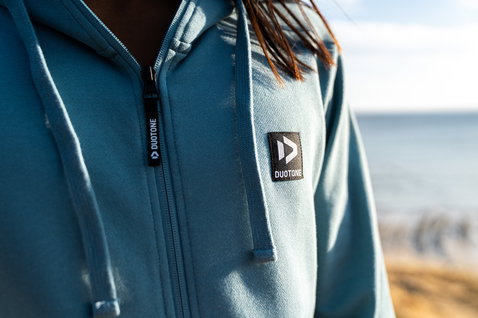 Zip hoody in steel blue during standing pose at the ocean beach