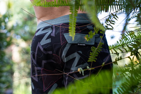Duotone Boardshorts DT 19inch boardshorts homme lors d'une pose dans une végétation tropicale luxuriante