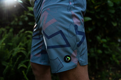 Duotone Apparel Boardshorts DT 19inch homme en bleu ardoise en pose extérieure parmi la végétation du jardin