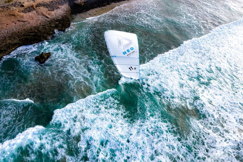 Duotone Neo Concept Blue LEI kite 11m while kitesurfing at a rocky coastline with breaking waves