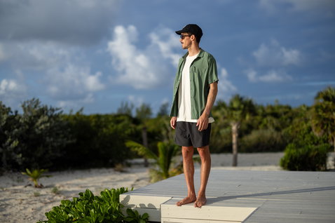 Duotone Apparel Shirt Wave SS Unisex Kurzarmhemd in olivgrün beim Tragen auf einer Holzterrasse am Strand