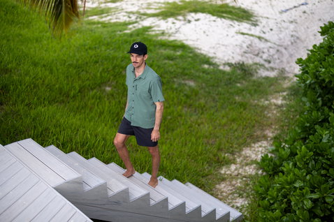Duotone Apparel Shirt Wave SS Unisex Kurzarmhemd beim Posieren am tropischen Sandstrand mit Palmen
