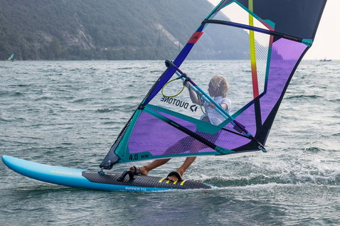 Duotone Ripper planche de windsurf pendant le windsurf sur un lac avec montagne en fond
