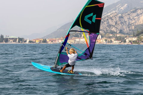Duotone Ripper planche de windsurf pendant le windsurf sur un lac alpin avec montagne et village