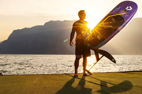 Duotone Stingray SLS windsurf board 116L in purple, yellow-green and silver grey at a mountain lake