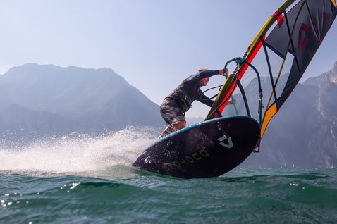 Duotone Eagle SLS windsurf board while windsurfing on a mountain lake, likely Lake Garda