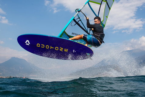 Duotone Eagle SLS windsurf board during windsurfing on an alpine lake with mountain backdrop