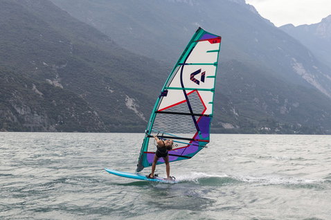 Duotone E_Pace HD voile de windsurf freeride lors d'une session sur un lac de montagne en turquoise, blanc et violet