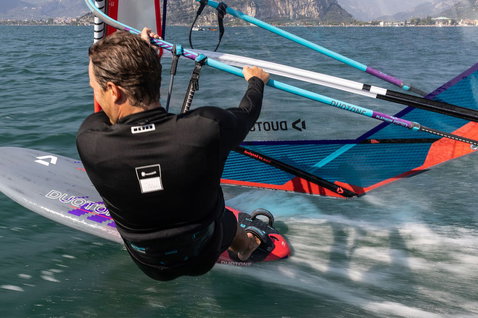 Duotone Jag SLS planche de windsurf lors d'une session de windsurf sur un lac avec un fond de montagne