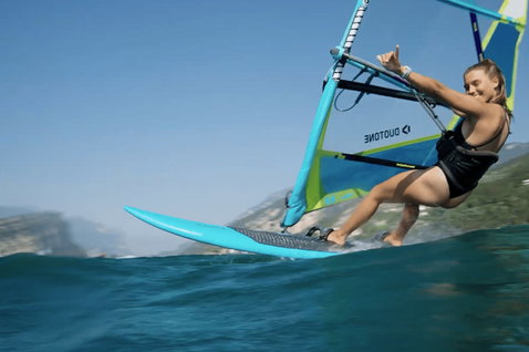 Duotone Windsurfing Eagle One Windsurf-Board beim Windsurfen an einem See oder Meer mit Felsklippen