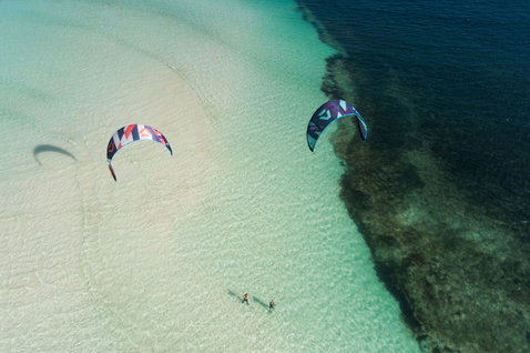 Duotone Evo SLS LEI Kite beim Kitesurfen in einer tropischen Lagune mit Korallenriff und weißem Sand