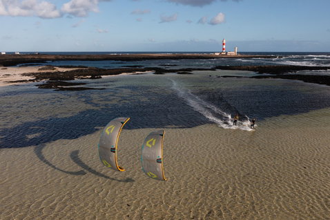 Duotone Neo D/LAB LEI kite during wave riding at an ocean beach with tidal lagoon and lighthouse