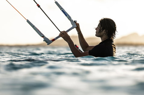 Duotone Click Bar Quad Control 2025 control bar during kitesurfing on open water with a distant coastline