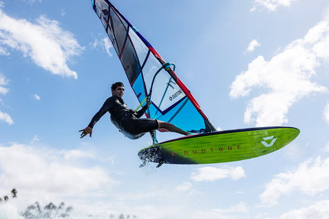 Planche de windsurf Duotone Ultra FreeWave SLS lors de windsurf en mer avec des arbres en arrière-plan