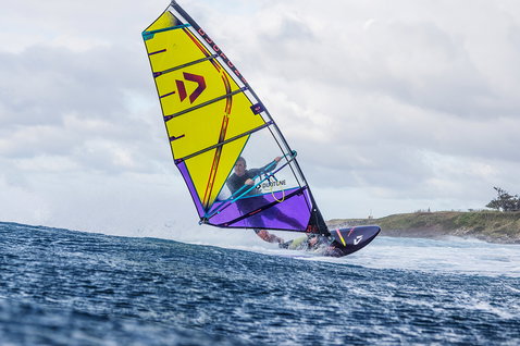 Planche de windsurf Duotone Ultra FreeWave SLS lors du surf de vagues sur une côte océanique avec promontoire rocheux