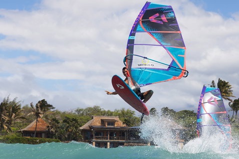 Duotone Duke 2025 wave sail during wave riding at a tropical coastal beach with palm trees