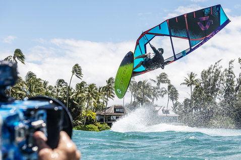 Duotone Duke wave sail during wave riding at a tropical ocean shore with palm trees