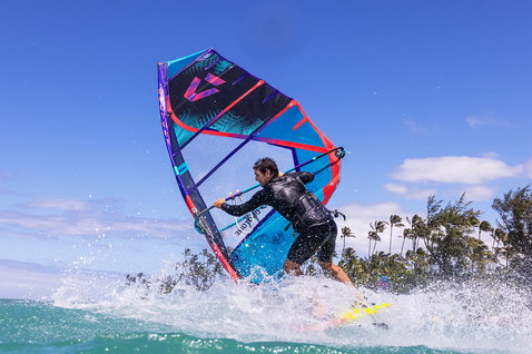 Duotone Duke wave sail during wave riding at an ocean beach with palm trees