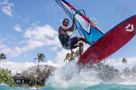 Duotone Ultra FreeWave 2025 windsurf board during wave riding at a tropical coastal ocean with palm trees