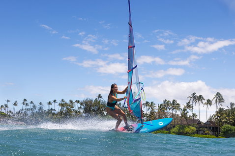 Duotone Ultra FreeWave 2025 windsurf board during wave riding in a tropical ocean lagoon with palm trees