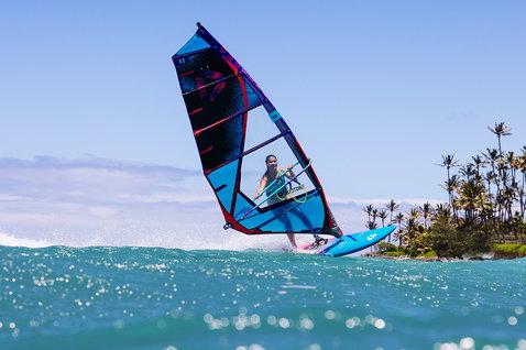 Duotone Ultra FreeWave windsurf board during wave riding in a tropical ocean with palm trees