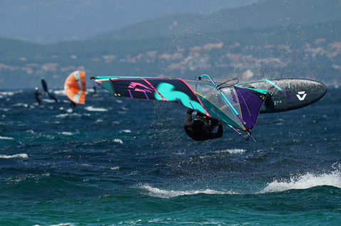 Duotone Skate SLS planche de windsurf en pratiquant le windsurf en mer ouverte avec montagnes côtières en arrière-plan