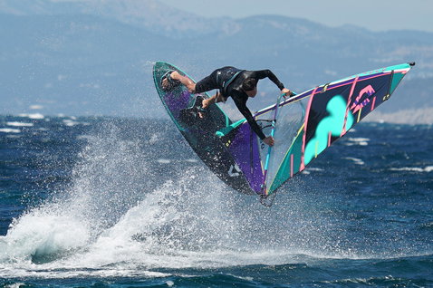 Duotone Skate SLS planche de windsurf lors du windsurf freestyle dans l'océan avec montagnes en arrière-plan