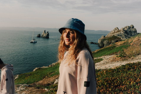 Bucket hat in slate blue during a standing pose at a coastal cliff with ocean view