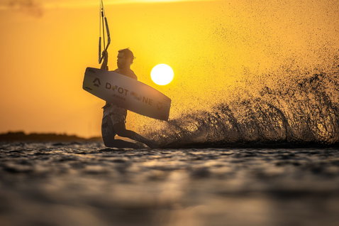 Kiteboard twin-tip Duotone Rebel SLS lors du kitesurf sur une plage océanique