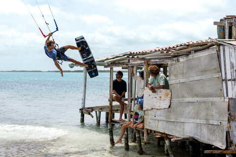 Duotone Rebel SLS LEI kite lors d'une session de kitesurf sur une plage de lagon tropical avec une cabane en bois