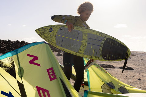 Duotone Blur D/LAB wave kiteboard en surf de vagues sur une plage avec roches volcaniques