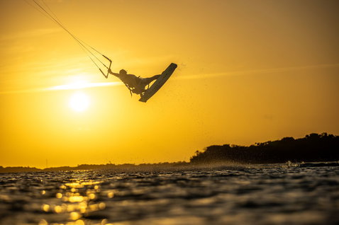 Duotone Jaime SLS Twin-Tip Kiteboard beim Kitesurfen in einer Ozeanlagune mit Baumsilhouetten