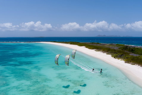 Duotone Select SLS twin-tip kiteboard while kitesurfing in a tropical ocean lagoon with white sand beach