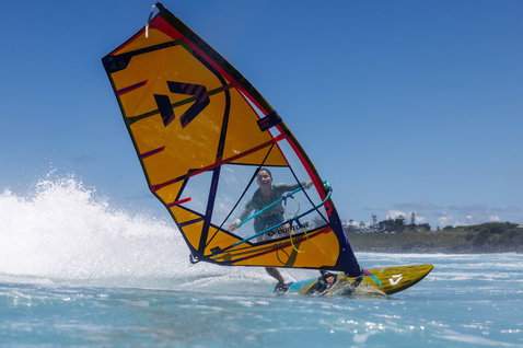 Duotone Grip 4 SLS windsurf board during wave riding at ocean beach with breaking waves