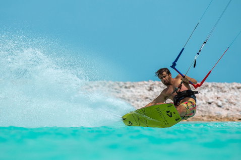 Duotone TS Big Air SLS twin-tip kiteboard during kitesurfing in tropical flat water ocean with rocky shoreline